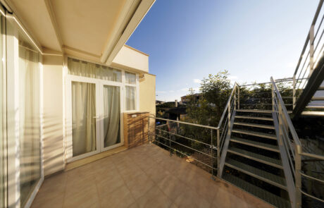 Terraza de una vivienda, se ve las puertas de acceso al interior y las escaleras de acceso a la parte superior