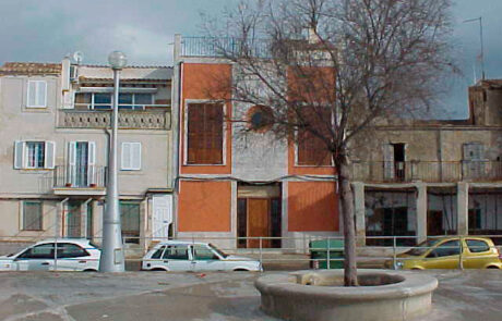 fachada de una iglesia convertida en vivienda, se ve también la plaza con un árbol